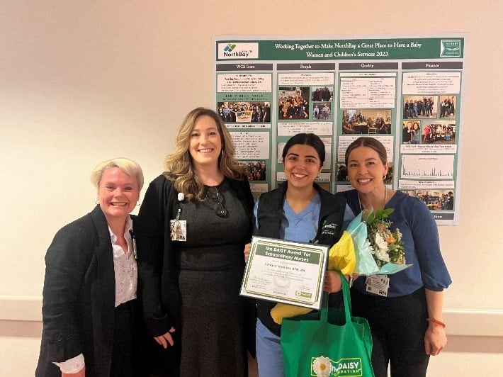 Three nurses standing with certificates and a poster board