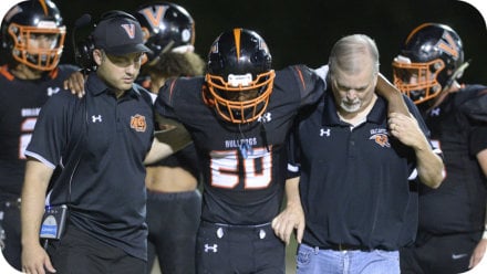 Dr. Peterson helping a football player off the field